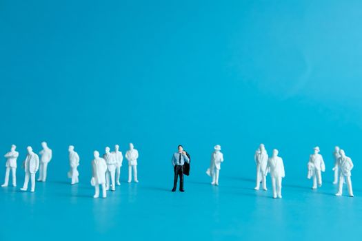 Miniature people concept - a different business worker standout from the crowd