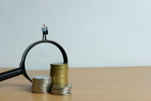 Miniature people concept - a businessman standing on magnifier glass, searching for financial solution