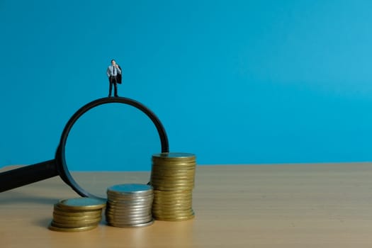 Miniature people concept - a businessman standing on magnifier glass, searching for financial solution