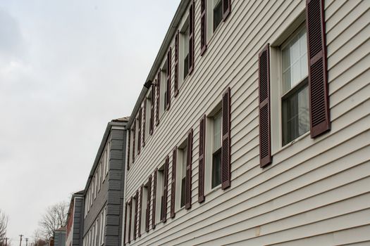 Repeating Windows With Brown Shutters on a White Apartment Building on a cloudy day