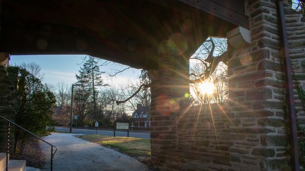 The Sun Shining Through a Window in a Cobblestone Wall in a Suburban Neighborhood