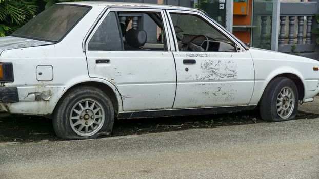 Old worn out and rusted abandoned car with flat tyre