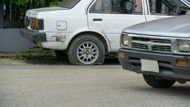 Old worn out and rusted abandoned car with flat tyre