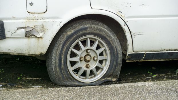 Old worn out and rusted abandoned car with flat tyre