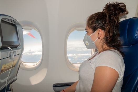 Real woman who wears a protective mask during an airplane trip. in time of coronavirus