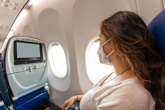 Real woman who wears a protective mask during an airplane trip. in time of coronavirus