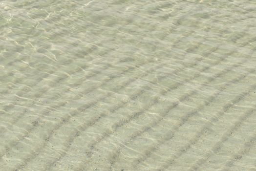 Sand under water. Glare on the sea surface