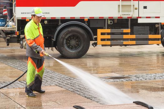 Harbin, Heilongjiang, China - September 2018: Man washes the pavement. Worker cleaning the street