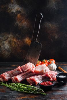 Fresh raw pork meat from organic farm with spices: pepper, salt, bay leaf. Butcher chopping cleaver in wood table over rustic wood and metal Food background side view .