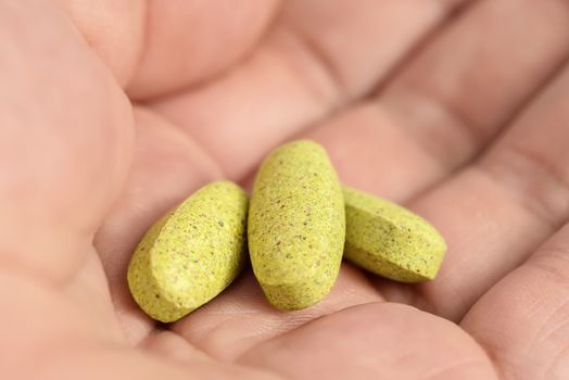 Herbal pills in hand. Herbal supplement in capsules.