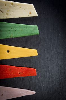 Pieces of colorful cheeses on black wooden background