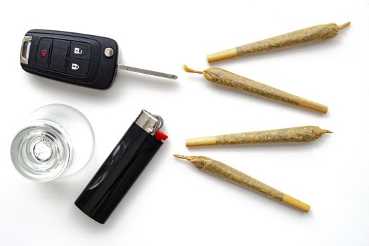 Cannabis Joints Cigarettes with car key, a shoot glass and a lighter on a white background. Concept driving high. Drug-impaired driving is dangerous and against the law