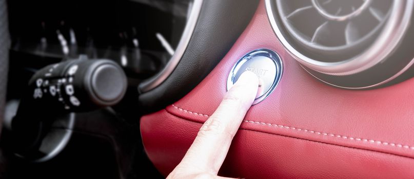 Close up of finger pressing the button to start the engine of a car.