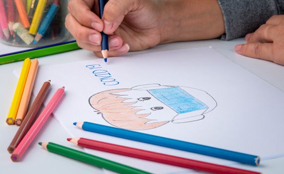 Close-up of a hand painted with color pencil, depiction of a man wearing a mask against the coronavirus.