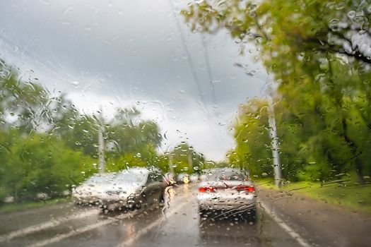 raindrops on the windshield of a car that is moving, driving on a country road in rainy weather