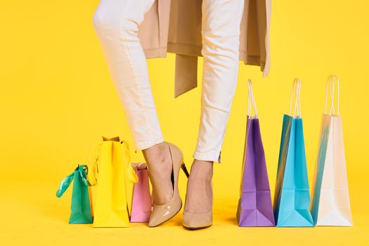 female feet in shoes packs shopping lifestyle yellow isolated background. High quality photo