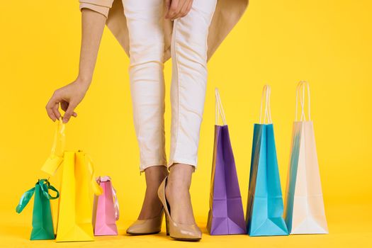 female feet in shoes packs shopping lifestyle yellow isolated background. High quality photo