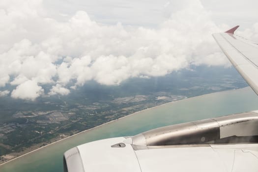 Flight from Bangkok to Surat Thani. View over blue water in Thailand with clouds and city panorama.