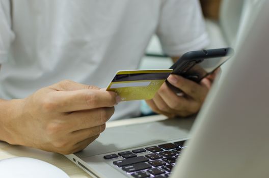 Man Shopping Online Using Laptop With Credit Card.Hands holding credit card and smartphone.