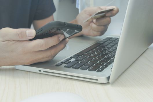 Man Shopping Online Using Laptop With Credit Card.Hands holding credit card and smartphone.