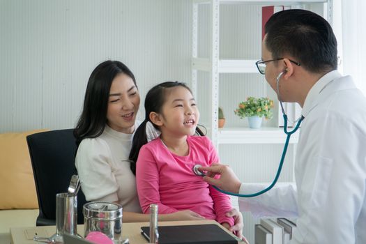 Happy Asian, adult mother and childhood daughter, checkup at the clinic.  pediatrician, listen to preschool girls' heartbeat. Male doctor, consultation and guidance of kid patients