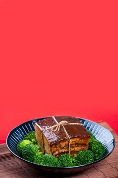 Dong Po Rou (Dongpo pork meat) in a beautiful blue plate with green broccoli vegetable, traditional festive food for Chinese new year cuisine meal, close up.