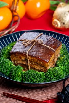 Dong Po Rou (Dongpo pork meat) in a beautiful blue plate with green broccoli vegetable, traditional festive food for Chinese new year cuisine meal, close up.