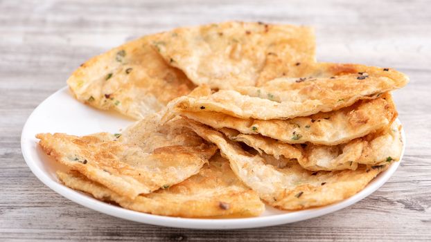 Taiwanese food - delicious flaky scallion pie pancakes on bright wooden table background, traditional snack in Taiwan, close up.