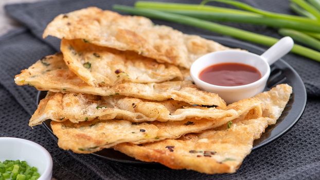 Taiwanese food - delicious flaky scallion pie pancakes on bright wooden table background, traditional snack in Taiwan, close up.