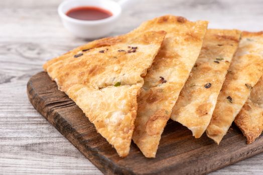 Taiwanese food - delicious flaky scallion pie pancakes on bright wooden table background, traditional snack in Taiwan, close up.