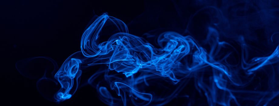 Conceptual image of blue color smoke isolated on dark black background, Halloween design element concept.