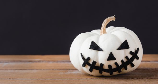 Funny Halloween day party concept ghost pumpkins head jack lantern scary smile on wooden table and black background, studio shot isolated, Holiday decoration