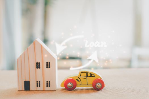 Home and car loan concept. Wooden home and car model with white arrow and loan text.