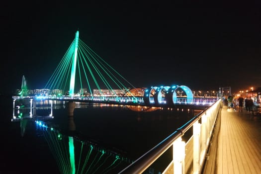 Night view of a beautiful scene of bridge over sea water in the evening time with colorful lights.