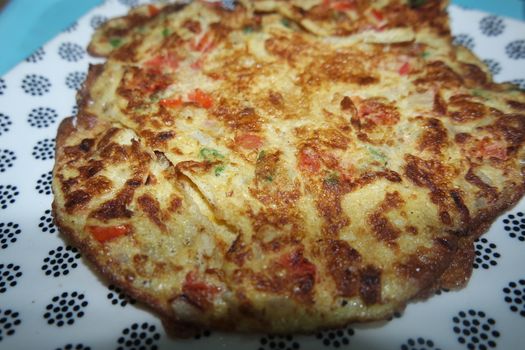 Close-up view with selective focus of egg omelet with peppers and spices sprinkled