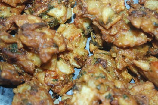 close-up view with selective focus of crispy basin pakora/pakoda or patties are popular indian or pakistani street food snack, served with green salad and sauce. Selective focus of