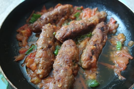 Closeup view of delicious spicy home made fried kebab with green mint leaves and green pepper sprinkled on it