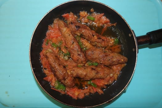Closeup view of delicious spicy home made fried kebab with green mint leaves and green pepper sprinkled on it