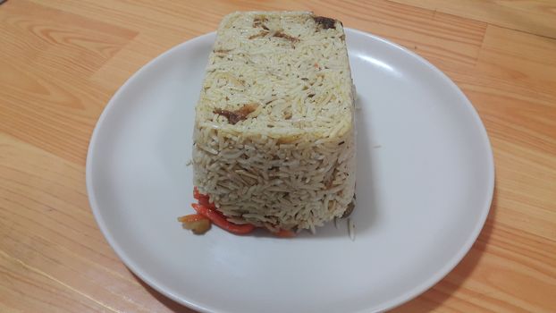 Closeup of frozen white rice cake in a white plate over wooden floor. Healthy food concept.