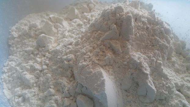 Closeup view of wheat flour heap placed in market for sale. White flour background
