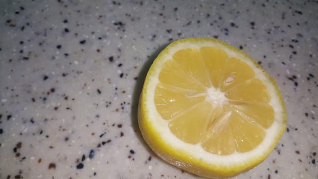 Fresh lemon slices with yellow peelings placed on a grey floor. Top view of fresh juicy lemon slice background