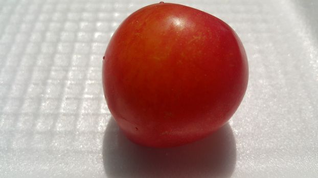 Closeup view of red plum on a white grey background. Freshly harvested plum making heart shape appearance in the view from angle.
