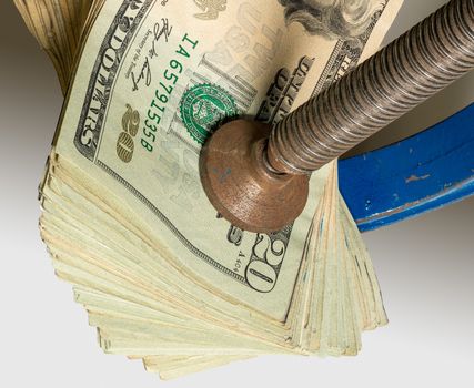 Concept for financial stress or recession. USA twenty dollar bills being squeezed between the jaws of a large vise or vice in detailed macro shot
