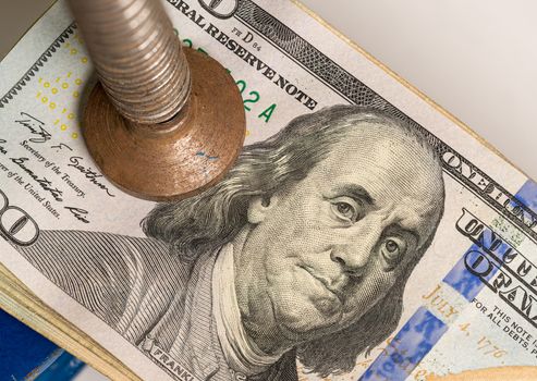 Concept for financial stress or recession. USA 100 dollar bills being squeezed between the jaws of a large vise or vice in detailed macro shot
