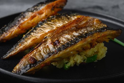 Grilled mackerel on plate with mashed potatoes.on grey textured background.
