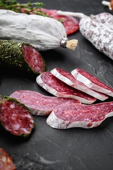 Set of dry cured salami, spanish sausages, slices and cuts on black background.