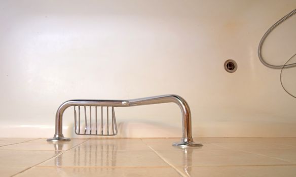 Old bathroom, brown tiled interior with bathtub, assistive handle