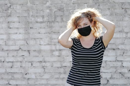 Portrait of a Girl in a protective mask free space for an inscription. Social distancing. White brick wall in the background. 