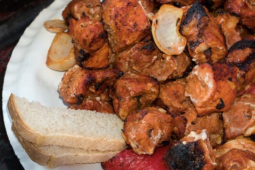 Pieces of fried meat lie on a plate with bread. Grilled shish kebab, barbecue or grill on a plate.