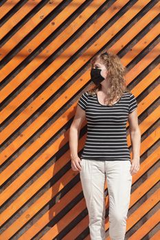 Portrait of a Girl in a protective mask free space for an inscription. Social distancing. Orange wooden wall in the background